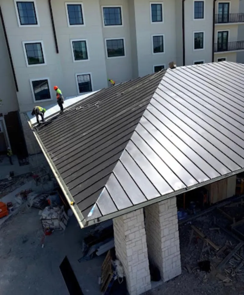 Crew installing standing seam metal roof panels on a commercial project in Bel Air